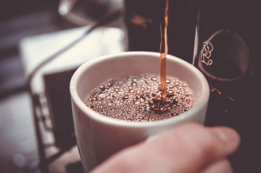 Coffee Maker - person holding white cup pouring coffee