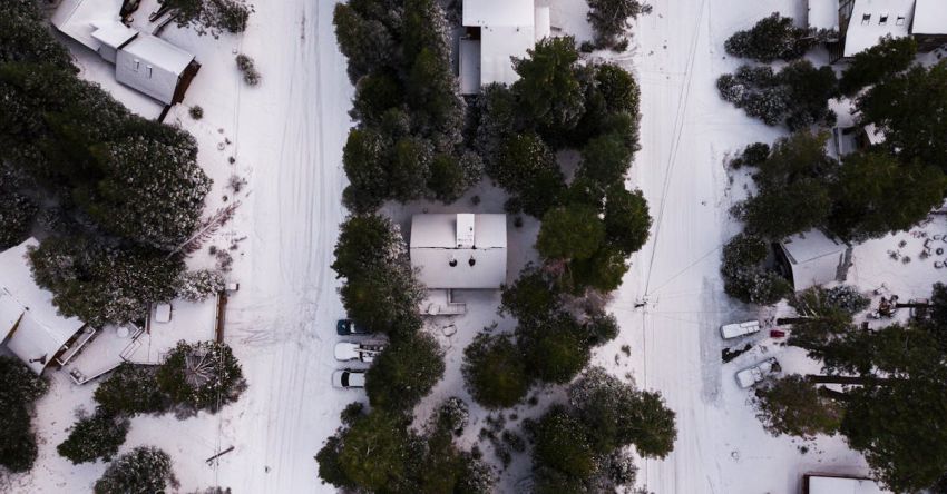 Drone - Areal Photography of Snow Covered Houses Surrounded by Green Trees