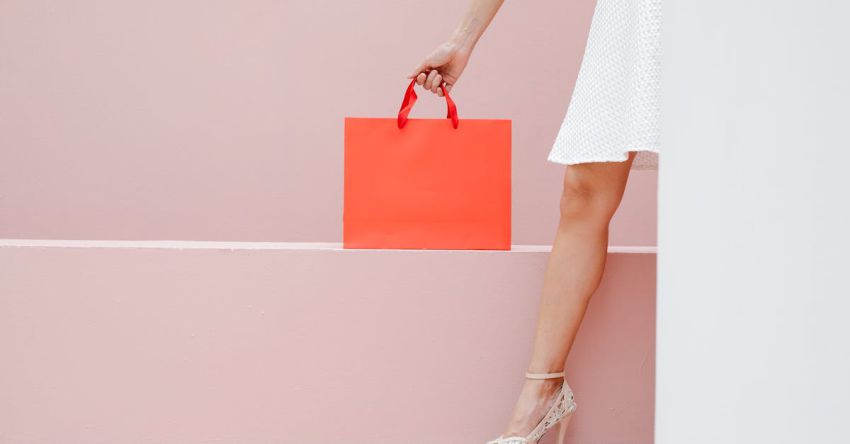 Clearance Sales - Crop anonymous stylish female in white dress and high heels carrying red shopping bag against pink wall